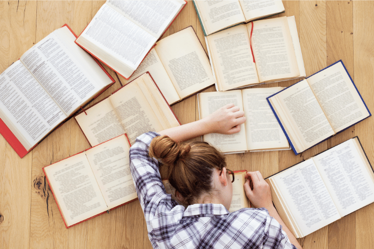 woman next to pile of open books