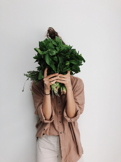 woman holding greens in front of face